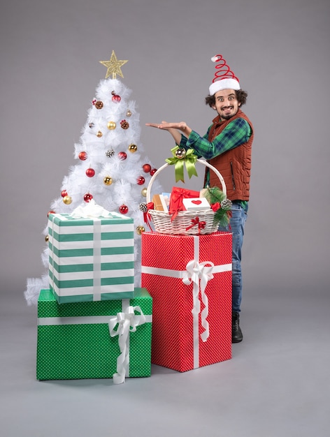 Vista frontal macho joven alrededor de regalos de vacaciones en la luz