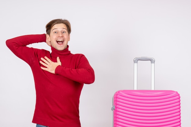 Vista frontal macho joven con bolsa rosa sobre fondo blanco emoción modelo viaje vacaciones vuelo verano color