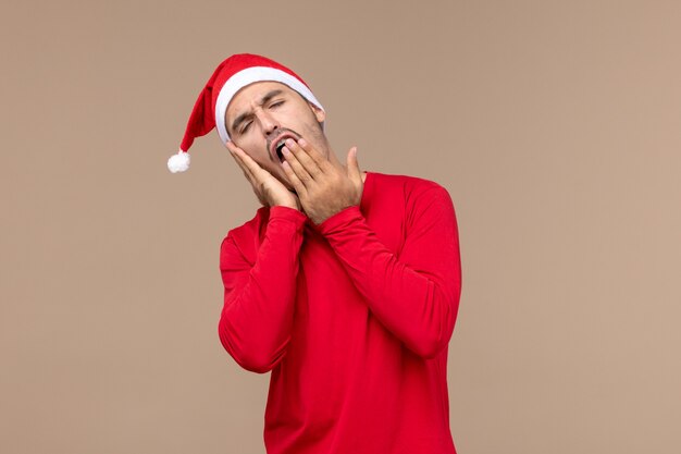 Vista frontal macho joven bostezando y tratando de dormir sobre fondo marrón emoción vacaciones de navidad