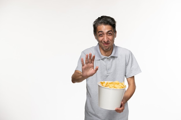 Foto gratuita vista frontal macho joven comiendo papas fritas riendo sobre superficie blanca