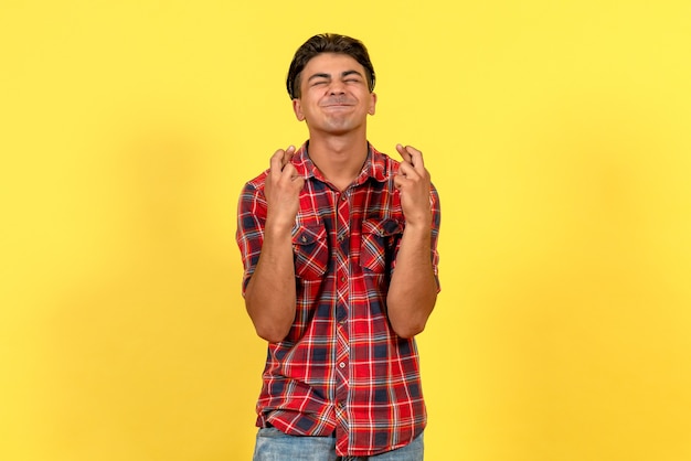 Foto gratuita vista frontal macho joven cruzando los dedos sobre fondo amarillo color de modelo masculino