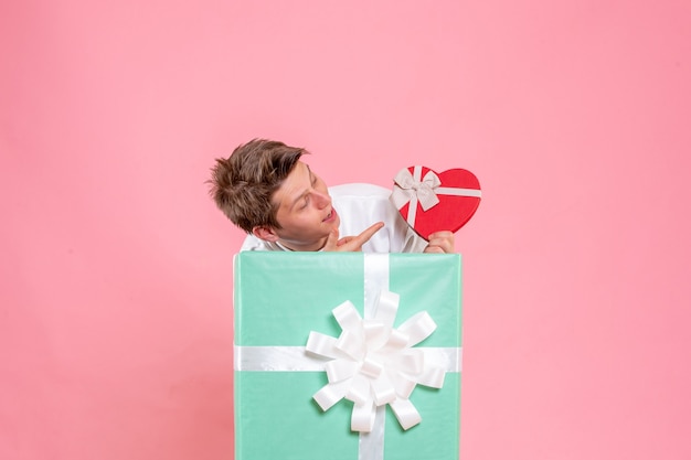 Foto gratuita vista frontal macho joven dentro presente con regalo sobre fondo rosa