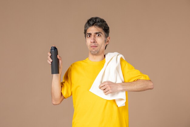 Vista frontal macho joven con espuma y toalla preparándose para afeitarse la cara sobre fondo de color rosa