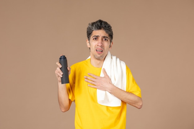 Vista frontal macho joven con espuma y toalla preparándose para afeitarse la cara sobre fondo de color rosa