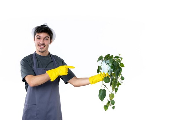 Vista frontal macho joven en guantes amarillos sosteniendo planta sobre fondo blanco flor hierba árbol jardinero trabajo verde arbusto jardín