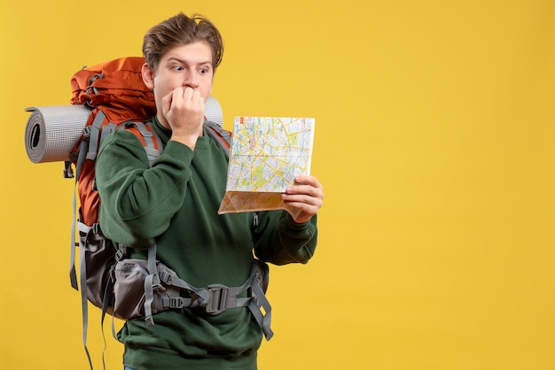 Vista frontal macho joven preparándose para senderismo sosteniendo mapa asustado