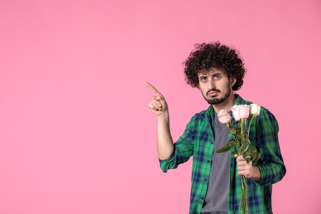 Vista frontal macho joven con rosas rosadas en rosa