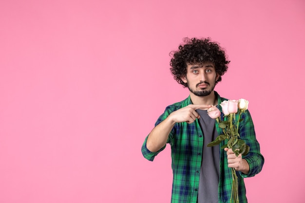 Vista frontal macho joven con rosas rosadas en rosa