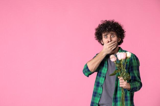 Vista frontal macho joven con rosas rosadas en rosa