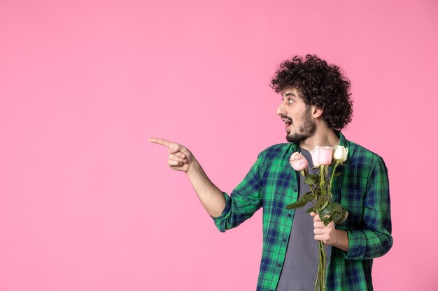 Vista frontal macho joven con rosas rosadas en rosas