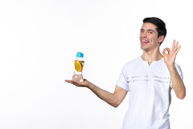 Vista frontal macho joven sosteniendo una botella de limonada sobre fondo blanco jugo de bebida fresca piel fruta hielo horizontal líquido soda humana