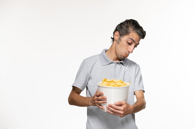 Vista frontal macho joven sosteniendo la cesta con papas fritas en la superficie blanca