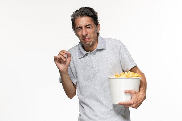 Vista frontal macho joven sosteniendo la cesta con papas fritas en la superficie blanca