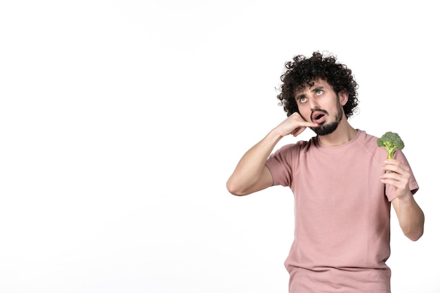 Vista frontal macho joven sosteniendo poco brócoli verde sobre fondo blanco cuerpo de ensalada peso horizontal dieta vegetal humana salud