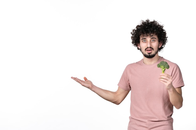 Vista frontal macho joven sosteniendo poco brócoli verde sobre fondo blanco cuerpo horizontal peso de salud de la dieta humana vegetal