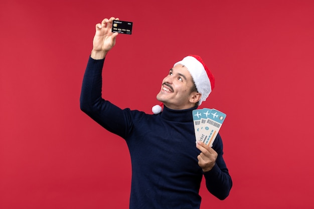 Foto gratuita vista frontal macho joven con tarjeta bancaria de billetes sobre fondo rojo.