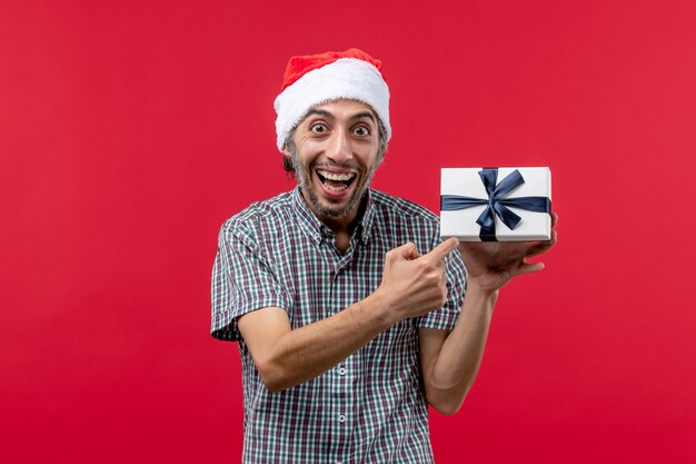 Vista frontal, de, macho joven, tenencia, regalo de navidad, en, rojo