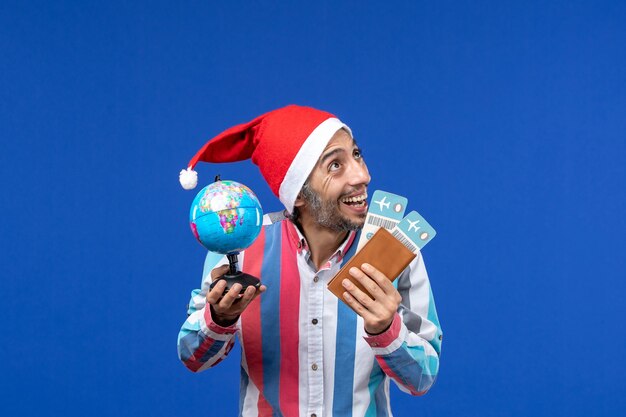 Vista frontal macho regular con boletos y globo en pared azul vacaciones año nuevo color