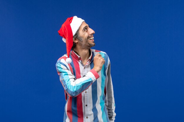 Vista frontal macho regular con gorro rojo de navidad en el piso azul vacaciones de navidad de santa