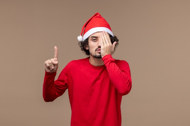 Vista frontal macho en rojo que cubre la mitad de su rostro sobre fondo marrón vacaciones emoción navidad