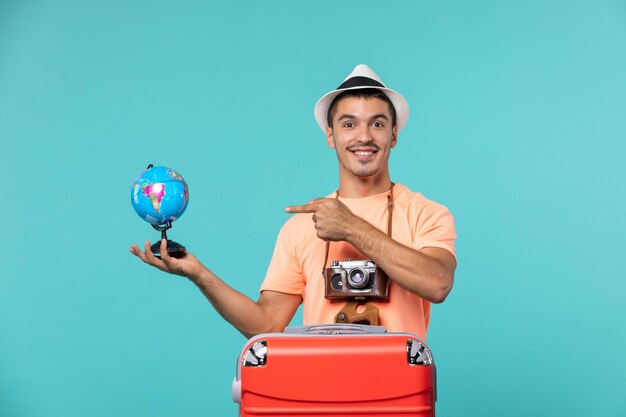 Vista frontal macho en vacaciones sosteniendo pequeño globo y sonriendo en azul