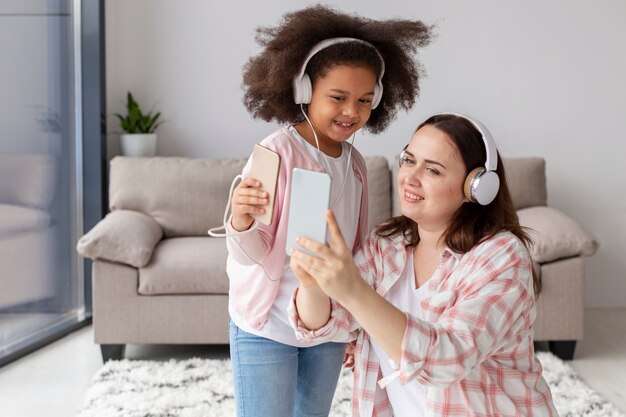 Vista frontal madre e hija escuchando música en casa