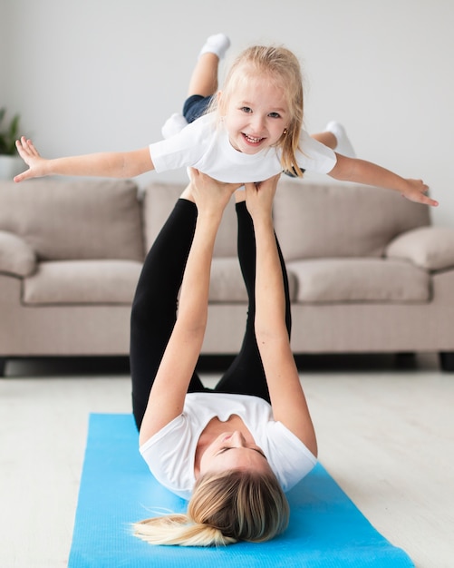 Vista frontal de la madre haciendo ejercicio con niño feliz en casa