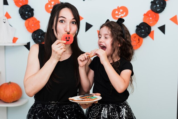 Vista frontal de la madre y la hija comiendo galletas