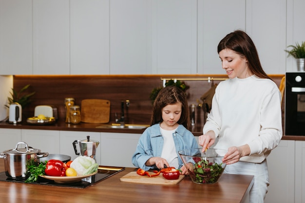 Vista frontal de la madre y la hija preparando la comida en la cocina