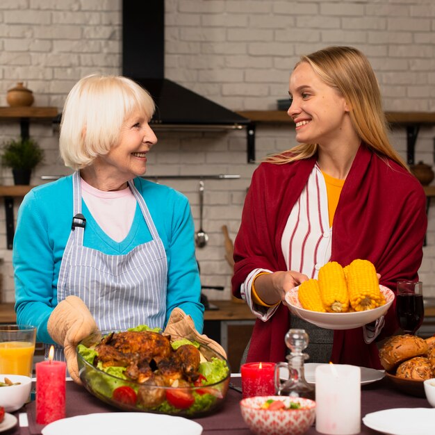 Vista frontal de la madre y la hija sosteniendo la comida y mirándose