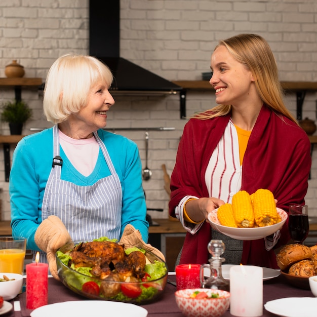 Vista frontal de la madre y la hija sosteniendo la comida y mirándose