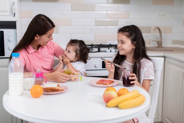 Vista frontal madre con hijas en la cocina