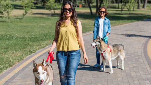 Vista frontal de la madre y el hijo paseando a los perros en el parque