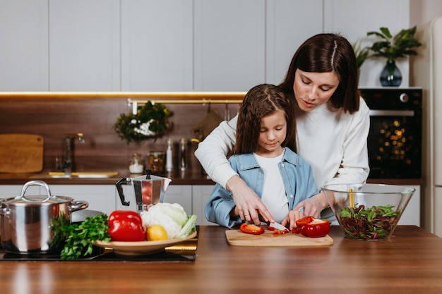 Vista frontal de la madre y la niña preparando la comida en la cocina