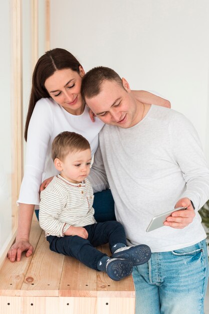 Vista frontal de la madre y el padre mirando el teléfono con el niño