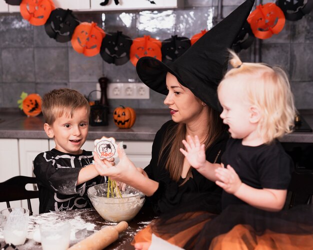 Vista frontal de una madre y sus hijos haciendo galletas de halloween