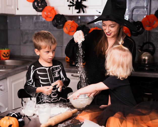 Vista frontal de una madre y sus hijos haciendo galletas de halloween