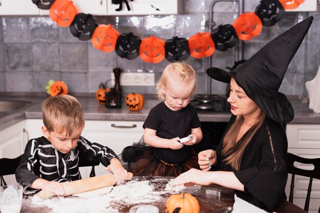 Vista frontal de una madre y sus hijos haciendo galletas de halloween