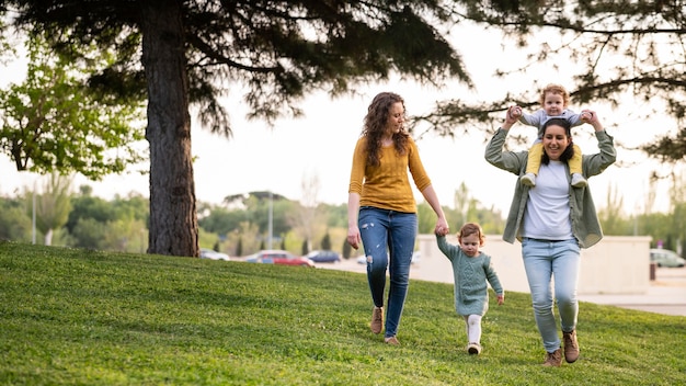 Vista frontal de madres lgbt afuera en el parque con sus hijos.