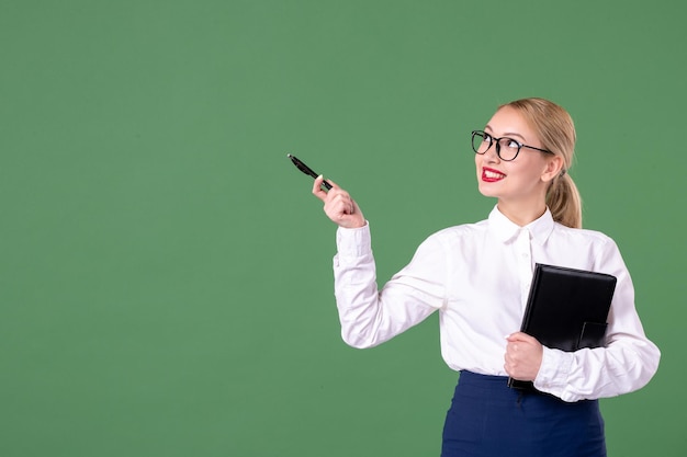 Vista frontal maestra en gafas de sol con bloc de notas y bolígrafo sobre fondo verde escuela estudio libro dinero trabajo uniforme estudiante documento mujer lección