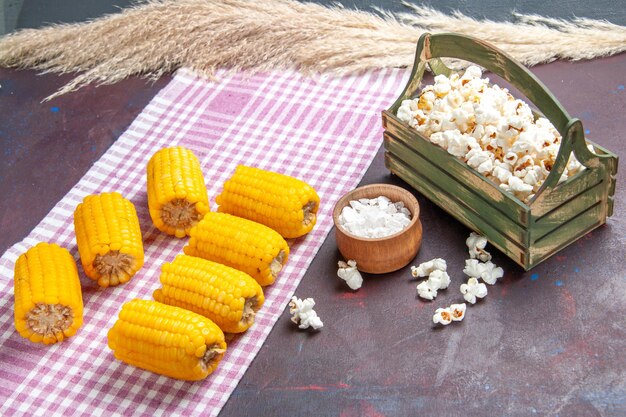 Vista frontal de maíz amarillo en rodajas crudo y fresco con palomitas de maíz en una superficie oscura alimentos vegetales crudos frescos