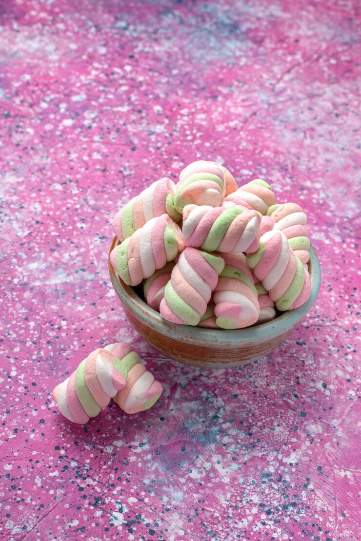 Foto gratuito vista frontal de malvaviscos de colores dulces poco formados dentro de una olla redonda en el escritorio rosa.