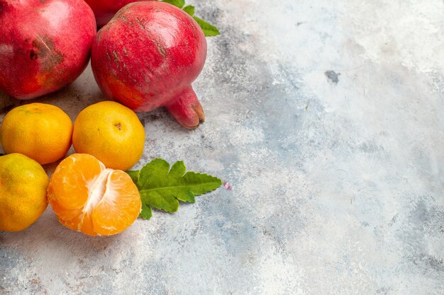 Vista frontal mandarinas frescas con granadas rojas sobre fondo claro sabor a vitamina árbol de color de fruta