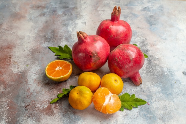 Vista frontal de mandarinas frescas con granadas sobre fondo claro sabor a fruta vitamina de árbol de color