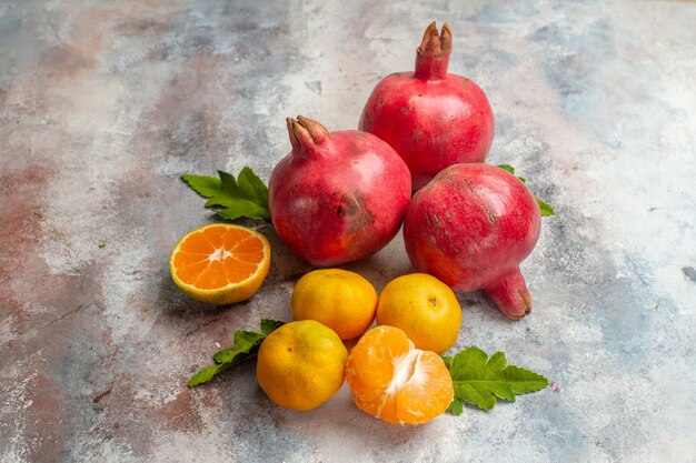 Vista frontal de mandarinas frescas con granadas sobre fondo claro sabor a fruta vitamina de árbol de color