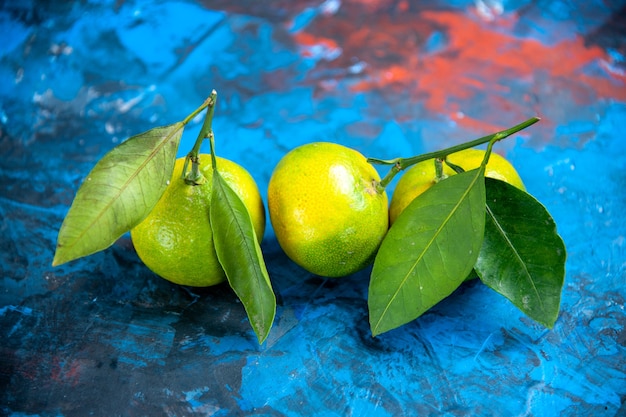 Vista frontal mandarinas frescas con hojas sobre fondo azul aislado