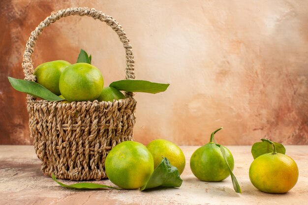Vista frontal mandarinas verdes frescas dentro de la canasta sobre fondo claro jugo foto color fruta suave