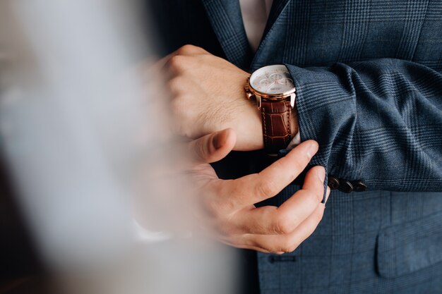 Vista frontal de una manga del traje de hombre y manos con elegante reloj