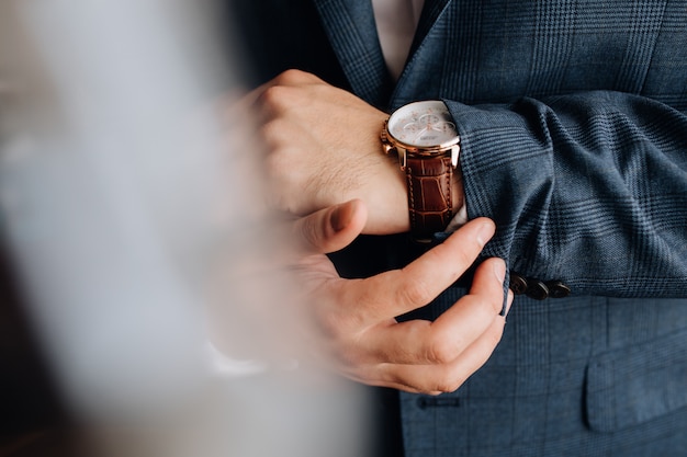 Vista frontal de una manga del traje de hombre y manos con elegante reloj