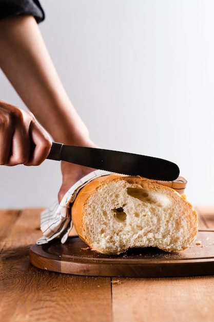 Vista frontal de la mano cortando pan